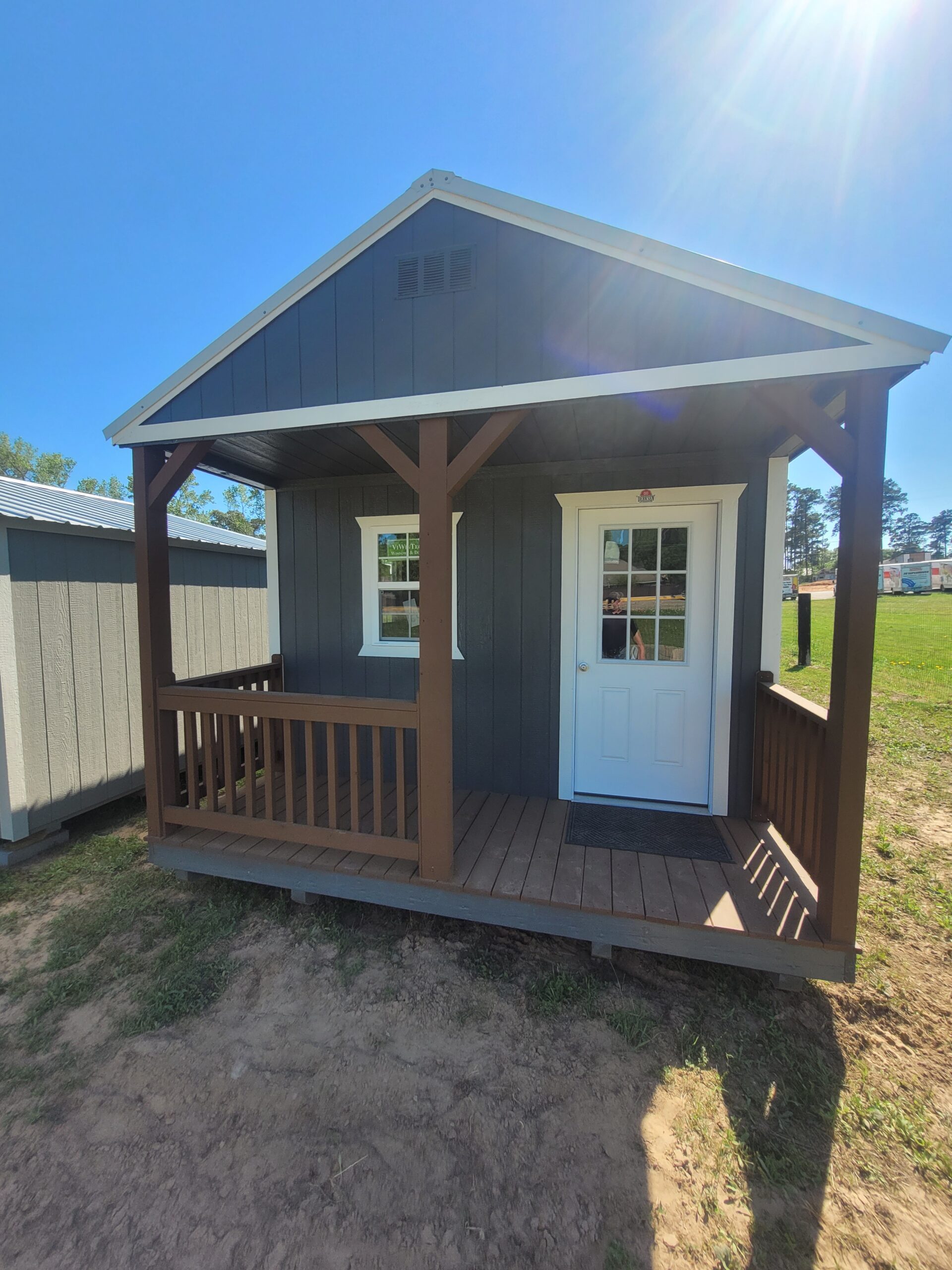 Backyard rustic cabin prepared for weekend guests with porch seating and shaded entry