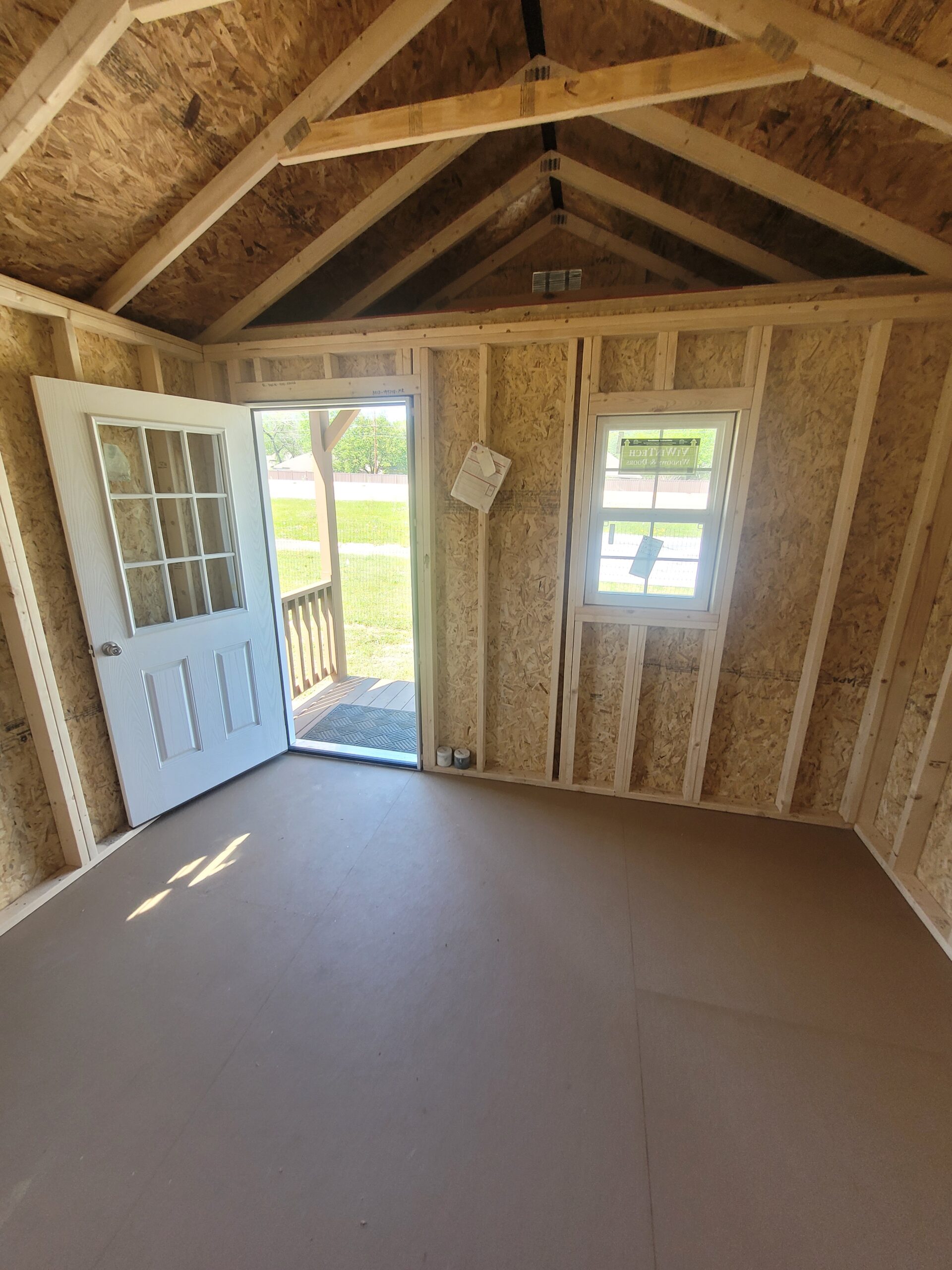 Rustic recreational building arranged for guest stays, hobbies, and comfortable private use, Shed Builder framing a custom storage shed beside a home with lawn equipment nearby