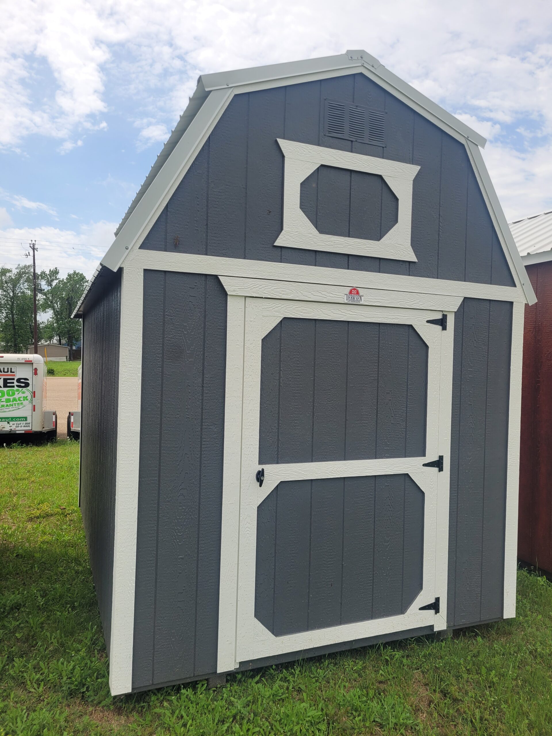 Portable barn placed beside backyard fence for mower, tools, and seasonal storage, Shed Builder installing wall panels on a backyard storage shed near gardening tools