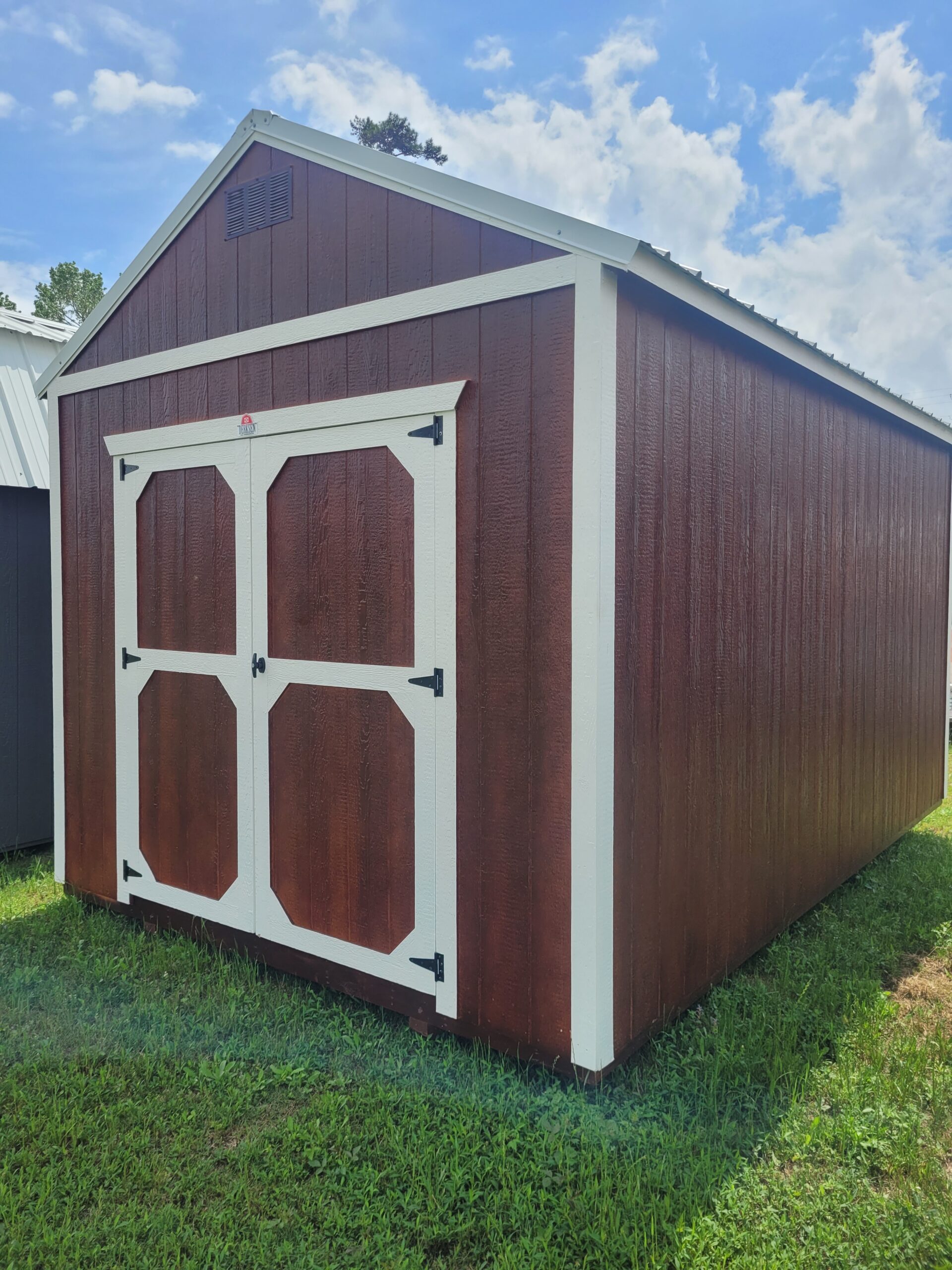 Utility building beside driveway storing tools, bins, and lawn equipment for daily access