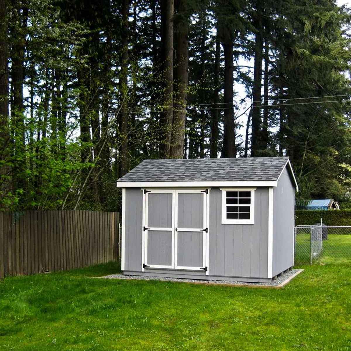 Backyard shed installed beside driveway for tools, mower, and seasonal storage access